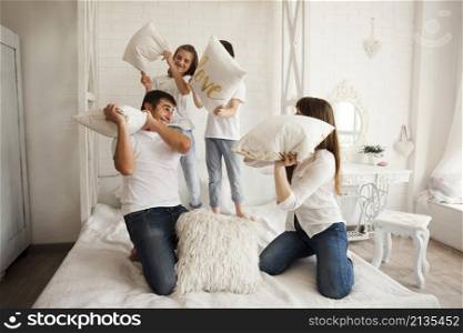 playful family having funny pillow fight bed