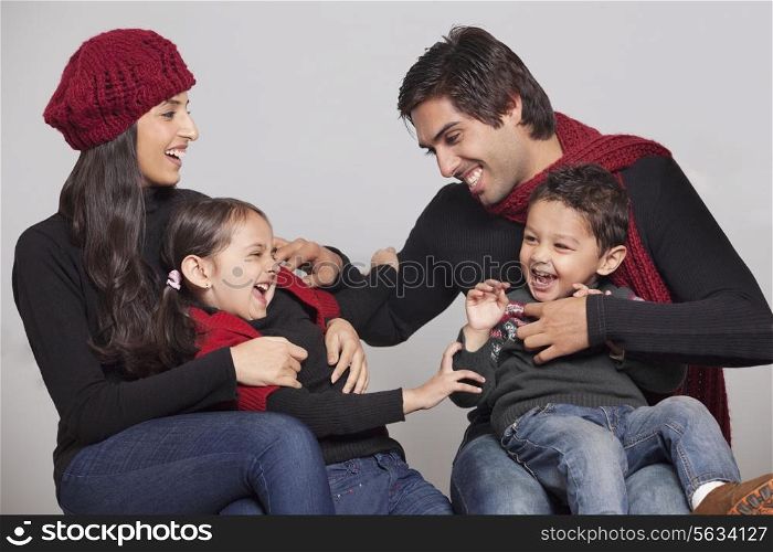 Playful family sitting over grey background