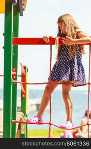 Playful girl on playground.. Time for fun. Summer holidays concept. Little funny girl having fun on playground. Child climbing. Enjoyable playful kid outdoors.