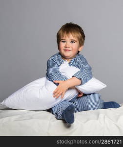 Playful little boy wearing blue pyjamas in bed