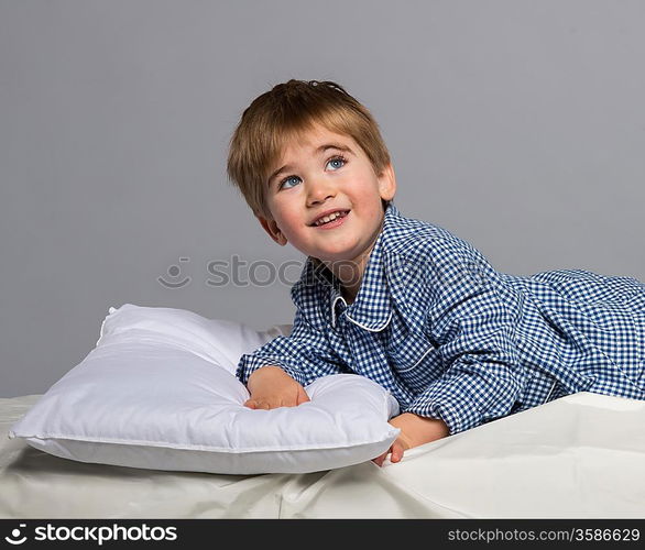 Playful little boy wearing blue pyjamas in bed