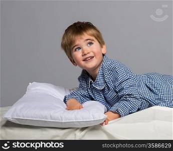 Playful little boy wearing blue pyjamas in bed