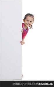 Playful little girl peeking through white board