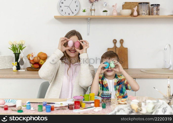 playful mom son covering eyes with painted eggs