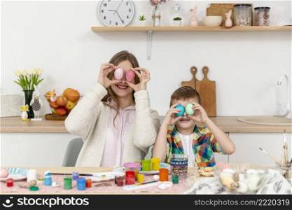 playful mom son covering eyes with painted eggs