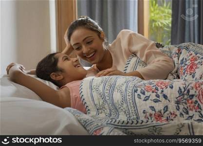 Playful morning, mother and daughter in bed