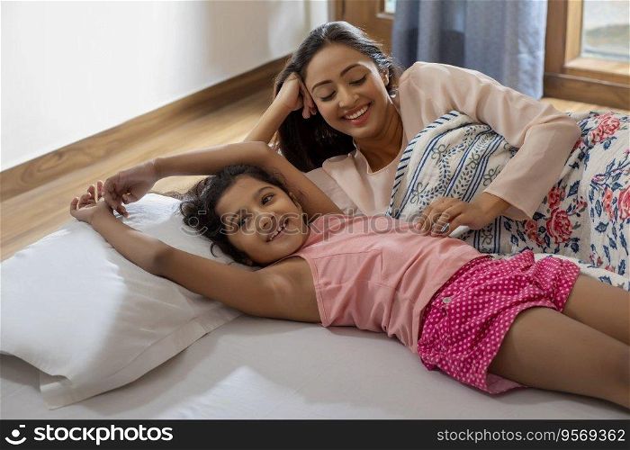 Playful morning, mother and daughter in bed