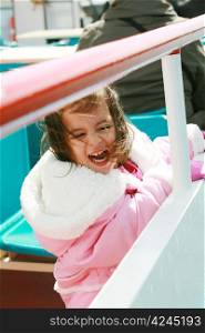 playful pretty little girl excited recreating in a ride on sail boat enjoying the spring