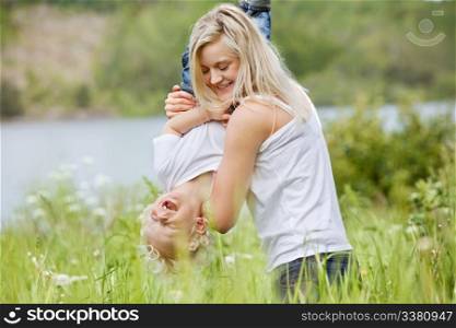 Playful woman in park playing with her laughing son