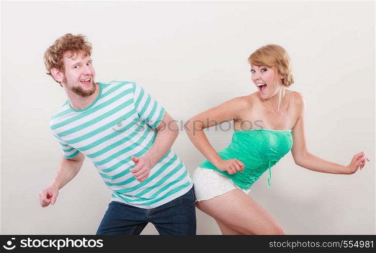 Playful young couple blonde girl and bearded guy on gray background,