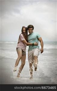 Playful young couple splashing in sea