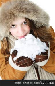 Playful young woman in winter coat with fur hood holding and tasting snow