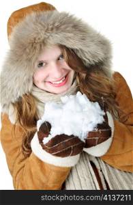 Playful young woman in winter coat with fur hood holding pile of fresh snow