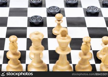 playing by different rules on the same board - black checkers and white chess figures on black white chessboard, pawn and checkers disc moves closeup  focus on the pawn 