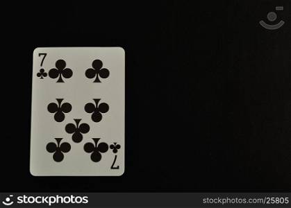 Playing card. Seven of clovers isolated on a black background