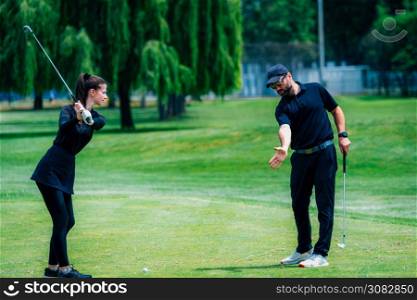 Playing golf. Young woman playing golf with golf instructor