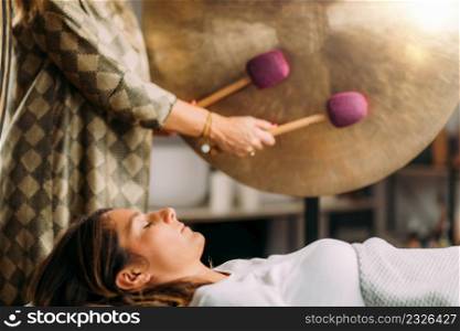 Playing gong in sound bath healing therapy . Gong in Sound Bath Therapy
