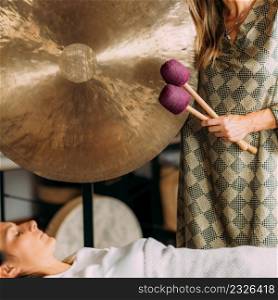 Playing gong in sound bath therapy . Sound Bath Therapy, Playing Gong