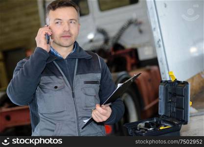 pleasant professional deliveryman holding mobile phone