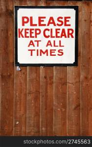 please keep clear at all times vintage sign at a wooden fence background