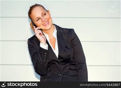 Pleased modern business woman talking on mobile near office building &#xA;