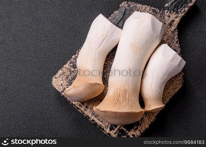 Pleurotus eryngii mushrooms on a dark concrete background. Raw whole edible mushrooms