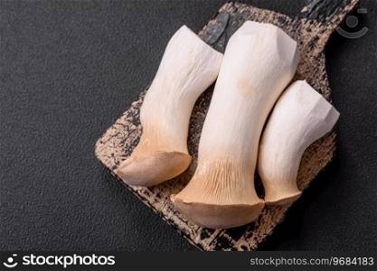 Pleurotus eryngii mushrooms on a dark concrete background. Raw whole edible mushrooms