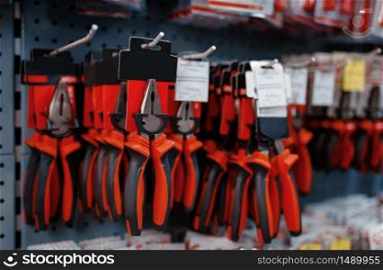 Pliers on racks in tool store closeup, nobody. Choice of equipment in hardware shop, professional instrument in supermarket. Pliers on racks in tool store closeup, nobody