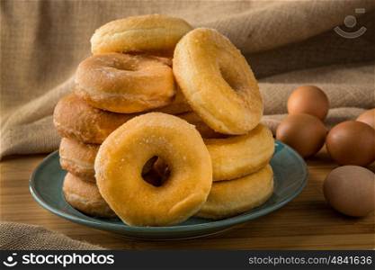 plle off fresh donuts in a plate with some eggs on background