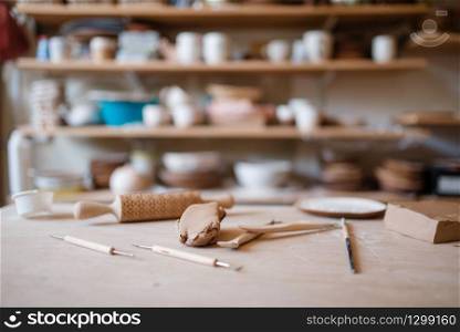 Plottery equipment on wooden table in workshop, nobody. Handmade clay tableware molding and shaping, traditional hobby, utensils making