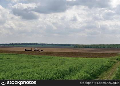 Ploughing field in spring. Tractor with trailer