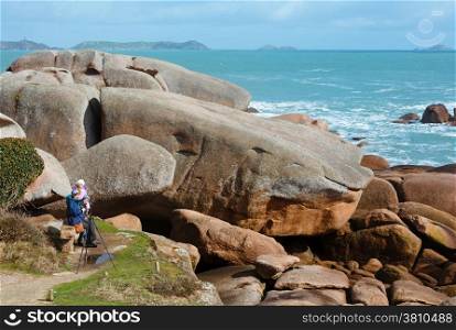 Ploumanach coast spring view and family on stony bench (Perros-Guirec, Brittany, France). The Pink Granite Coast.