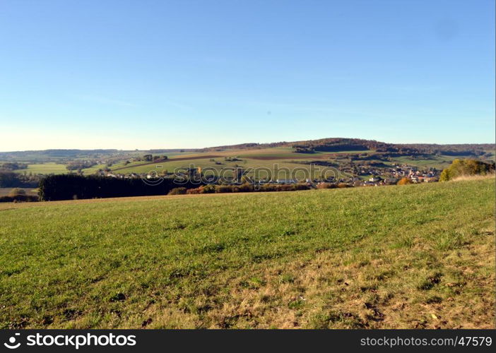 Plow fields with a background hill and a village