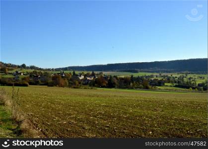 Plow fields with a background hill and a village
