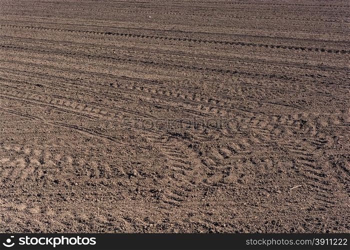 Plowed fertile soil with tractor traces - cultivated land