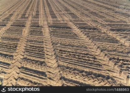 Plowed field agriculture in Austrian small village. Tractor tracks in soil. Plowed field brown soil tractor tracks