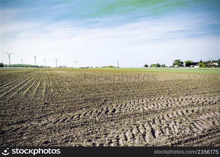 Plowed fields in Austrian landscape with modern wind turbines producing energy. Vintage style