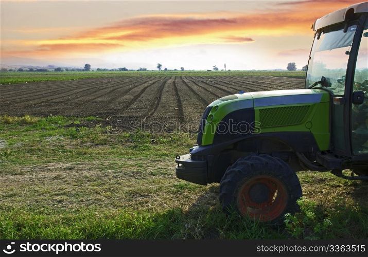 Plowed land and tractor on sunset