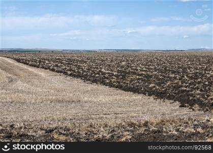 Plowed part of agricultural field in countryside landscape