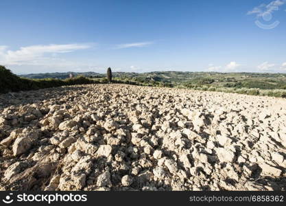 Plowed sloping hills of Tuscany in the autumn. Rural landscape with field after harvest.