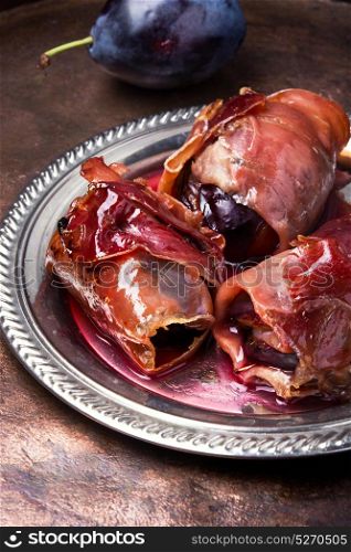 plum baked in jamon. spicy spanish dish jamon with plum on a retro background