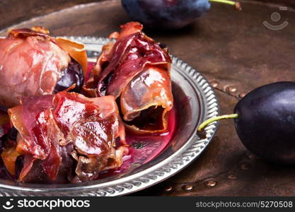 plum baked in jamon. spicy spanish dish jamon with plum on a retro background