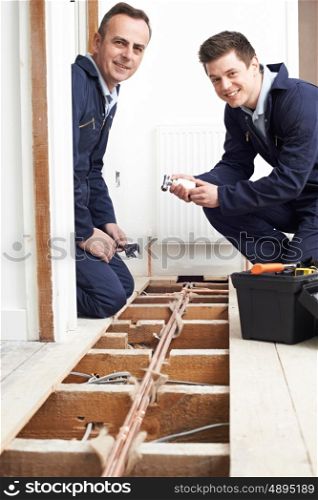 Plumber And Apprentice Fitting Central Heating in House