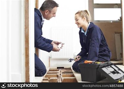 Plumber And Female Apprentice Fitting Central Heating