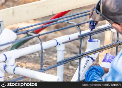 Plumber Applying Pipe Cleaner, Primer and Glue to PVC Pipe At Construction Site.
