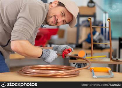 plumber cutting a copper pipe with a pipe cutter