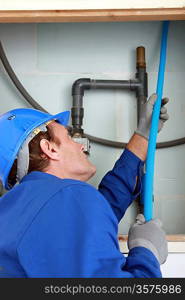 Plumber feeding blue pipe behind a false wall