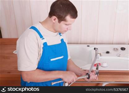 Plumber fitting a tap on a kitchen sink