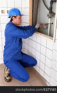 Plumber fixing a pipe to a wall