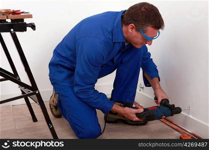 Plumber fixing copper pipe to wall